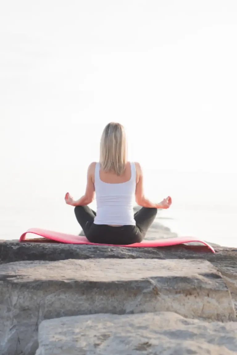 Jeune fille qui médite le dos tourné sur un rocher